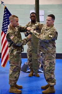 Commanding Officer Lt. Col. Jason Sabovich and Command Sgt. Maj. Chad Weber furls the battalion colors in preparation for the unfurling of the newly established 401st Cyber Battalion's colors as Master Sgt. Quientin Abston holds the staff.