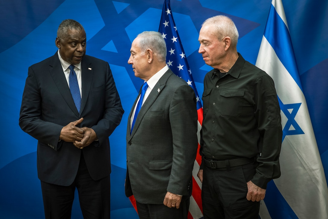 Defense Secretary Lloyd J. Austin III, Israeli Prime Minister Benjamin Netanyahu and Minister of Defense Yoav Gallant stand before American and Israeli flags.