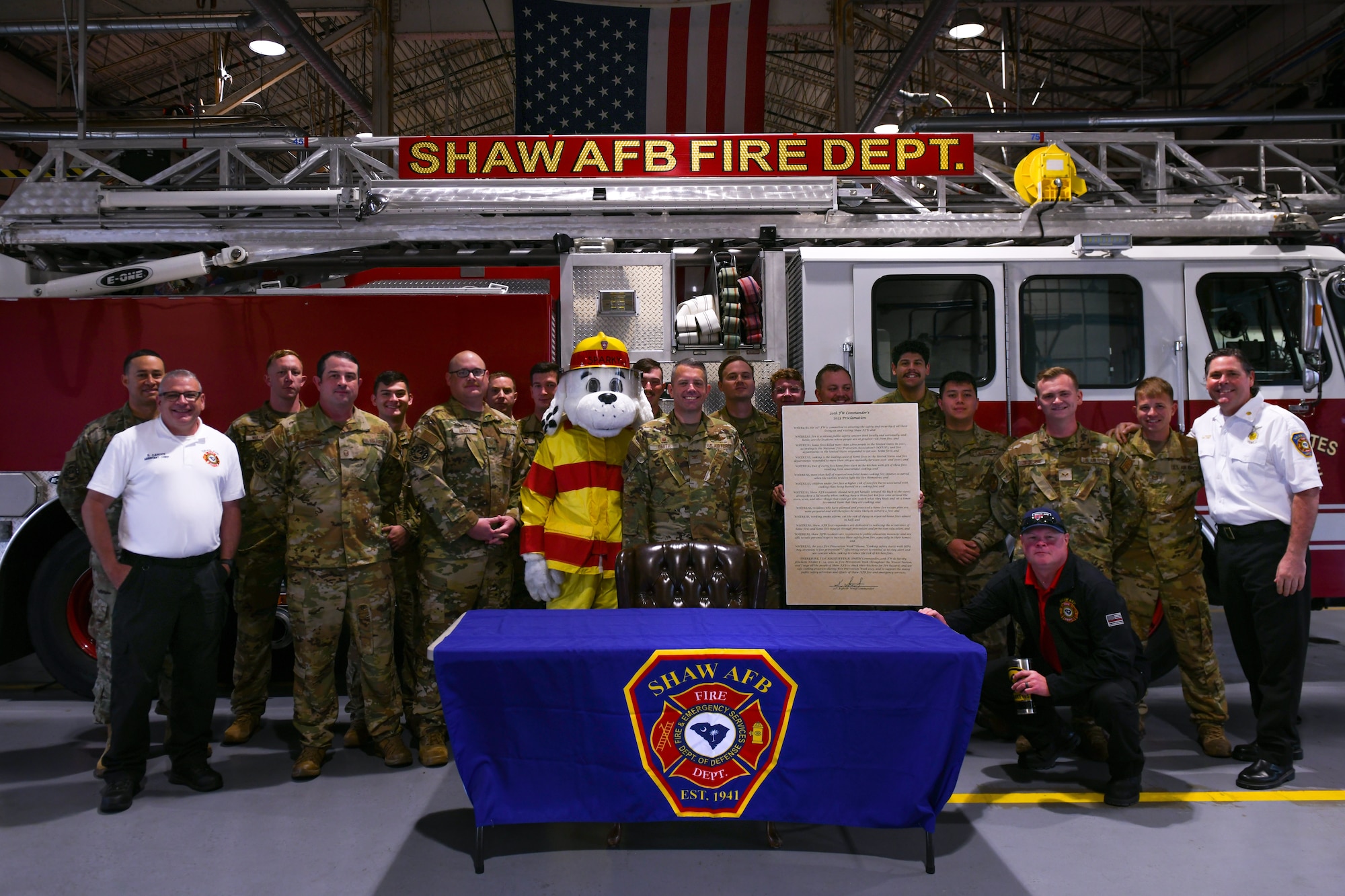 A group of military members pose for a photo in front of a fire truck.