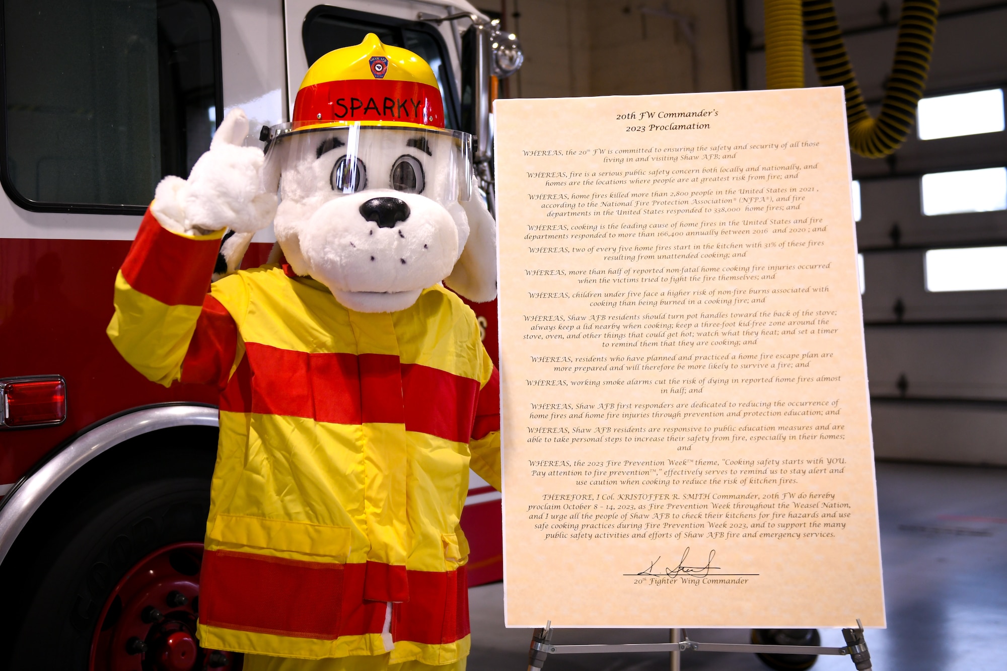 A fireman dog Sparky costume poses next to a Fire Prevention Week proclamation paper.