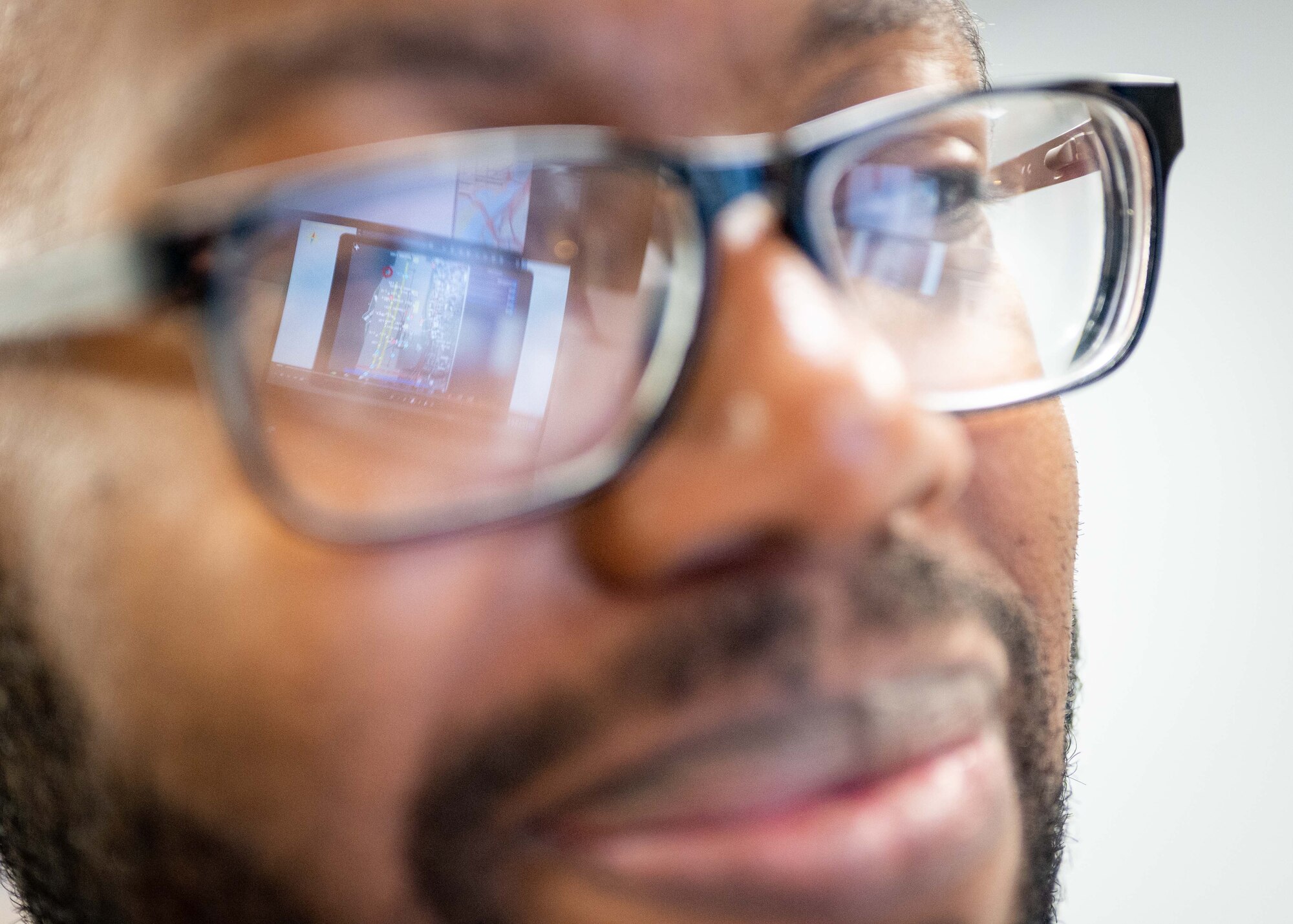 A computer screen reflects on an Airman's glasses.