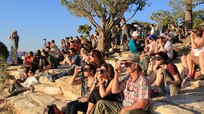 A crowd uses handheld solar viewers and solar eclipse glasses to safely view a solar eclipse.