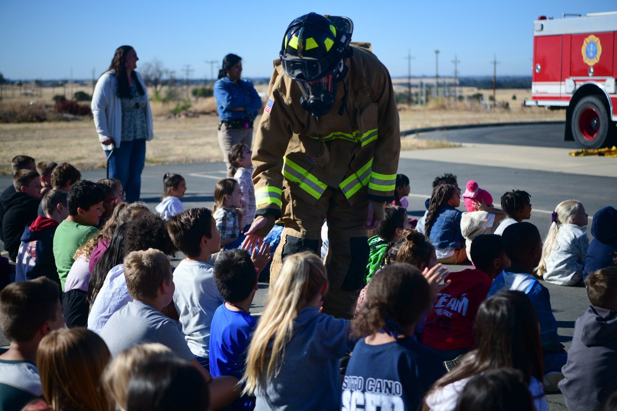 U.S. Air Force Airman 1st Class Kace Kauffman, 9th Civil Engineer Squadron firefighter, gives high fives to the children at Lone Tree Elementary School on Beale Air Force Base, California, Oct. 11, 2023.