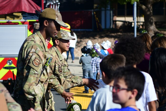 The 9th Civil Engineer Squadron firefighters pass out toy fire helmets to students at Lone Tree Elementary School on Beale Air Force Base, California, Oct. 11, 2023.