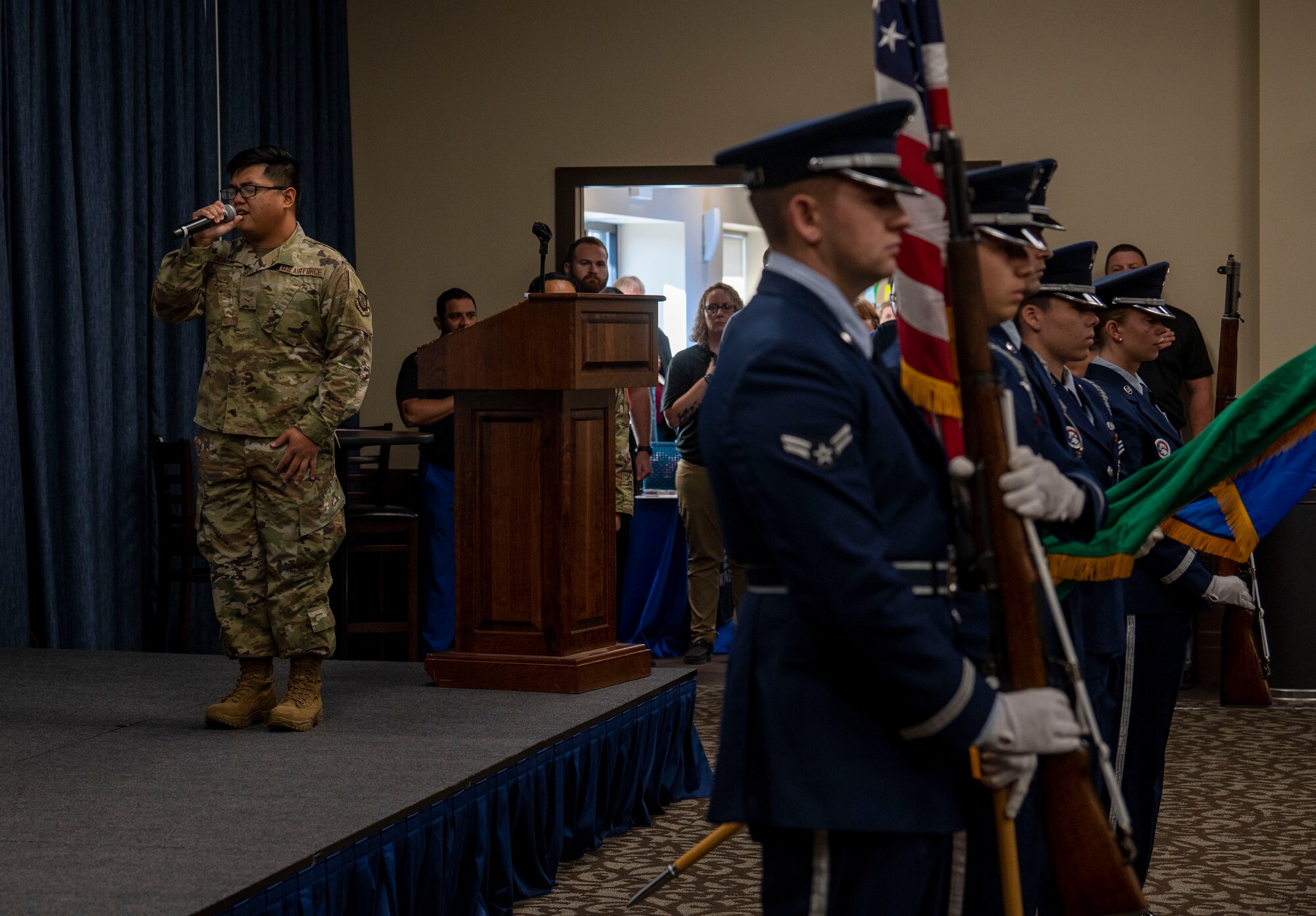 An Airman sings the national anthem on stage.