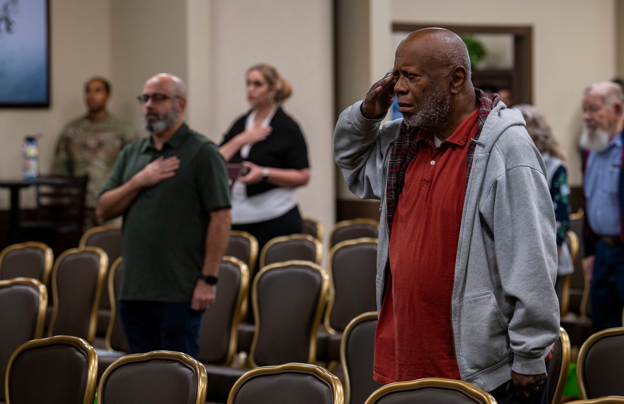 A military retiree salutes during the national anthem.