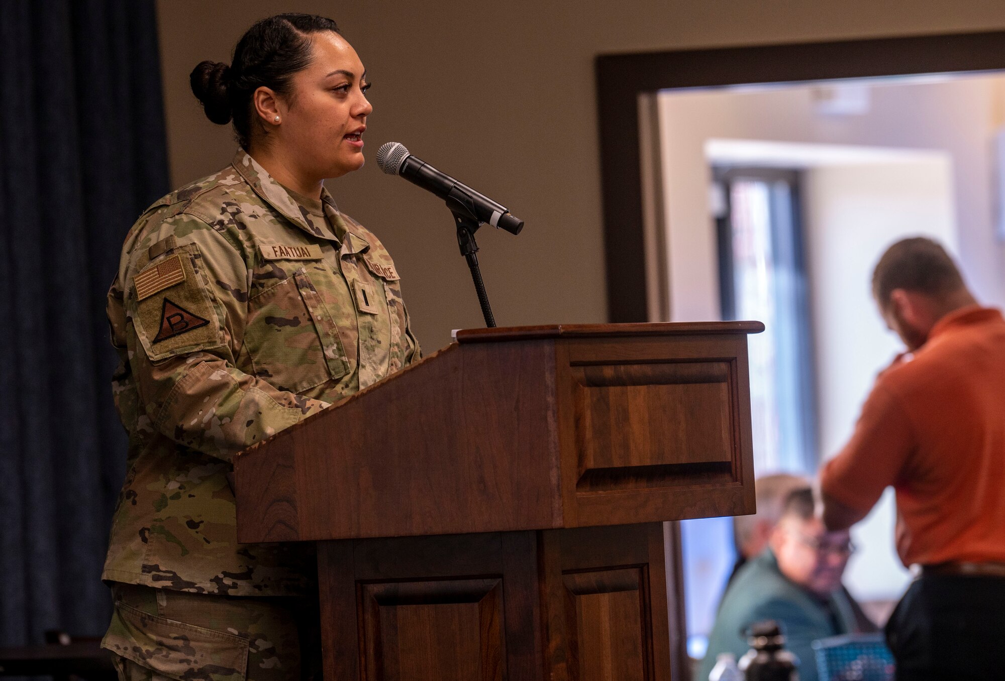 1st Lieutenant Raylyn Faatuai speaks into a microphone during an opening remarks ceremony.