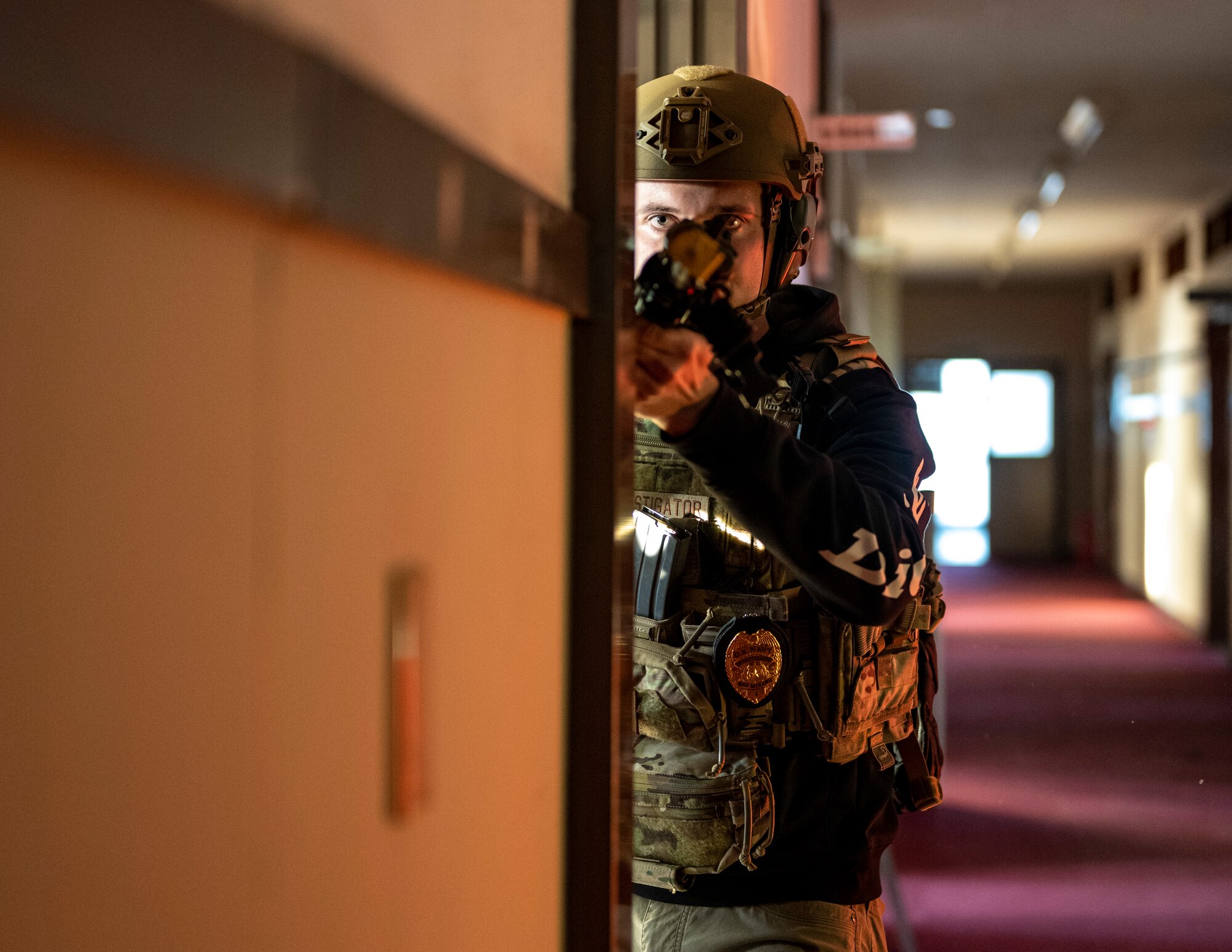A security forces member peeks around door corner.