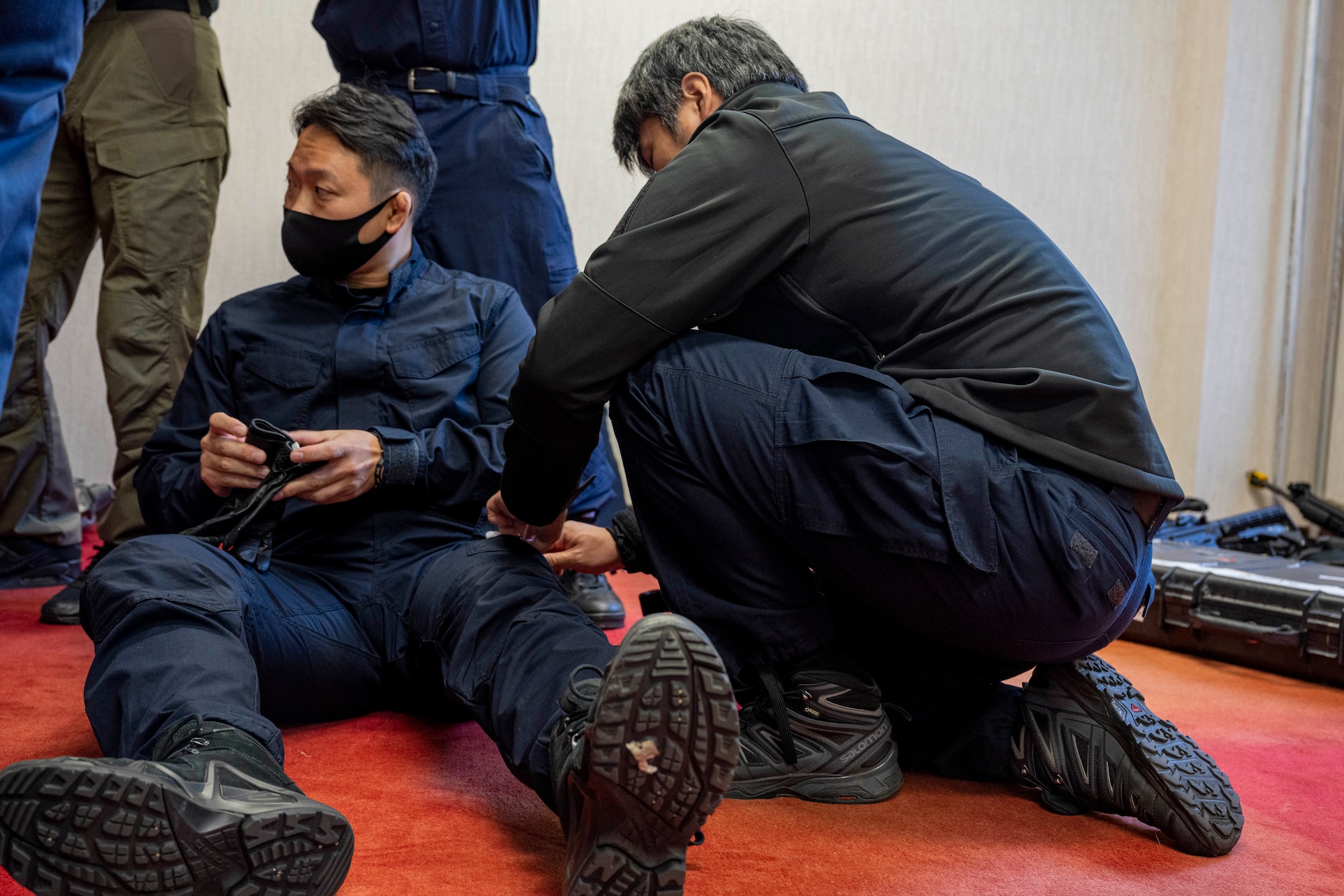 A police officer applies a tourniquets to another police officer legs.
