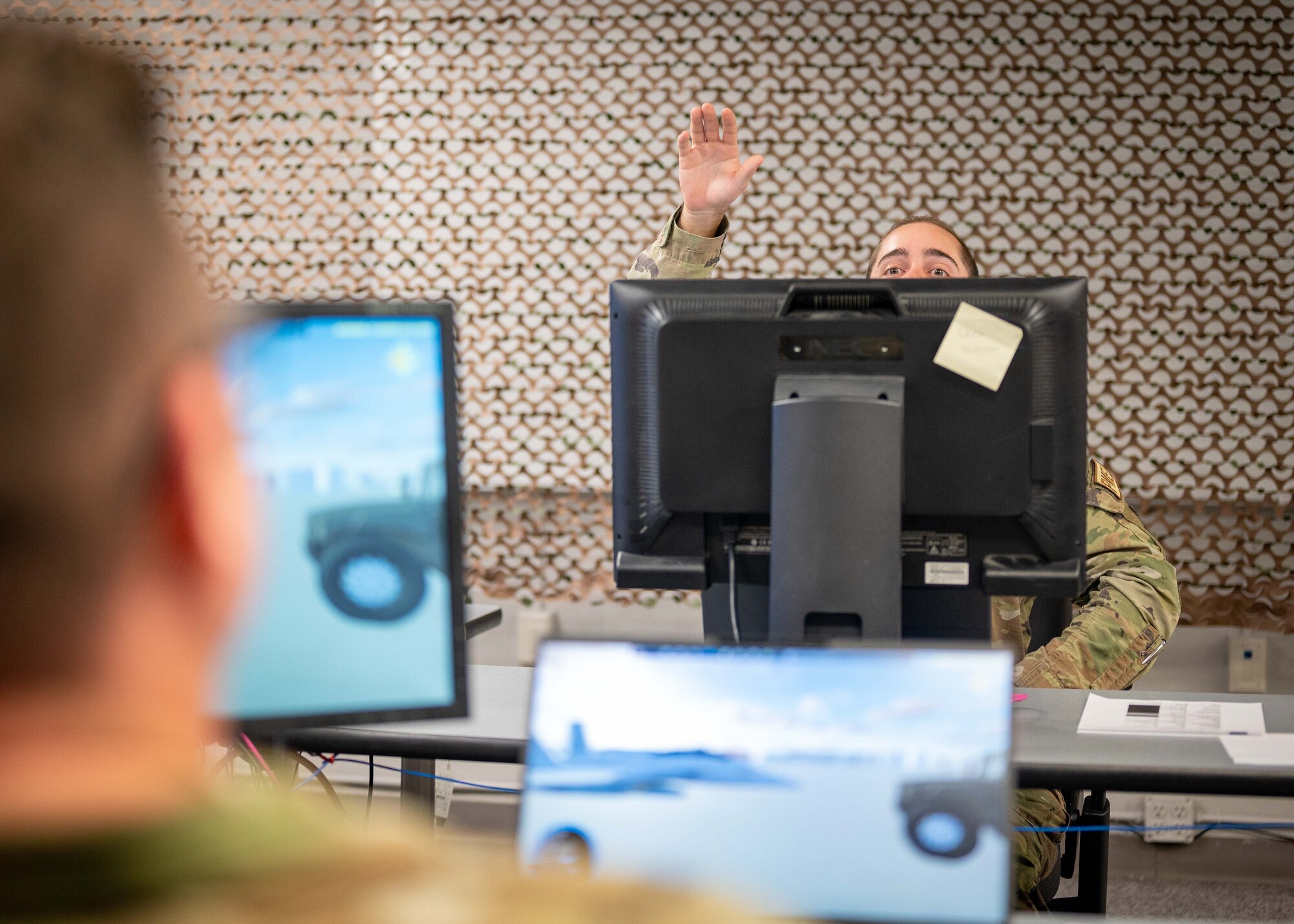 An Airman peeks over his screen to call a teammate.