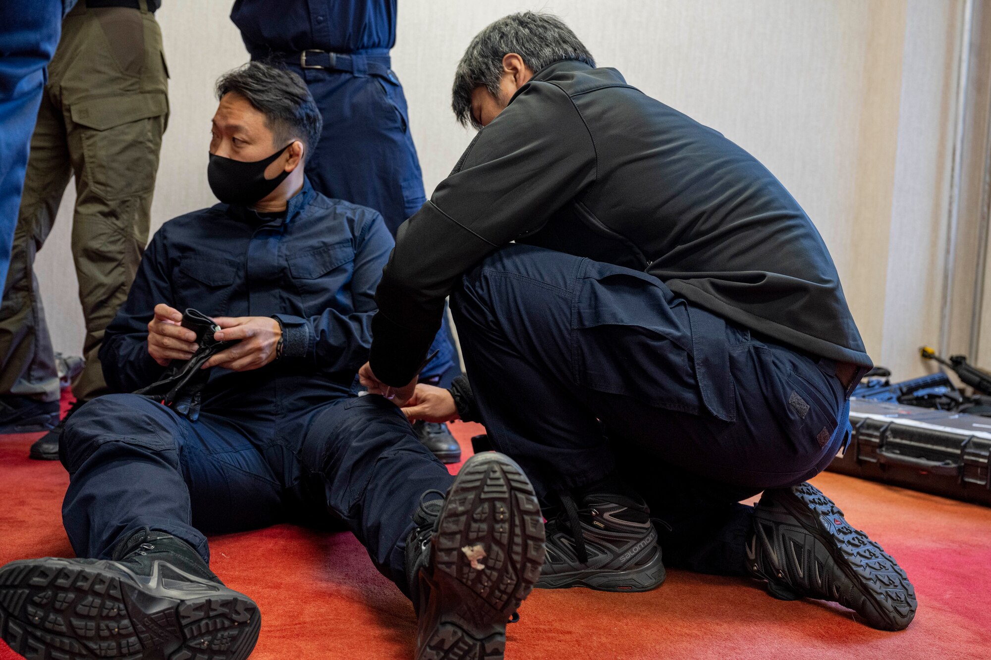 A police officer applies a tourniquets to another police officer legs.