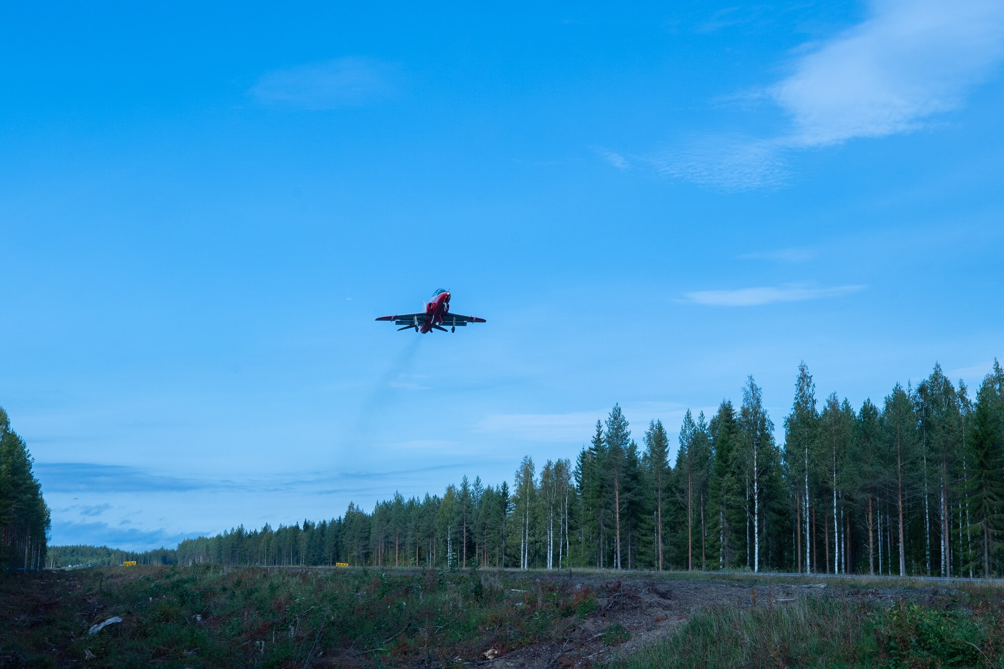 A photo of an airplane flying over a highway.