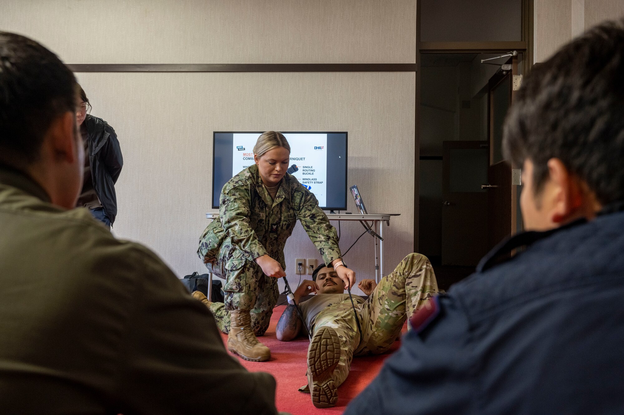 A sailor performs medical care on a simulated injured Airman.
