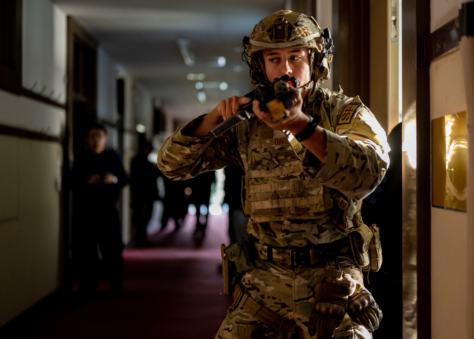 Airman guards a hallway with rifle pointed.