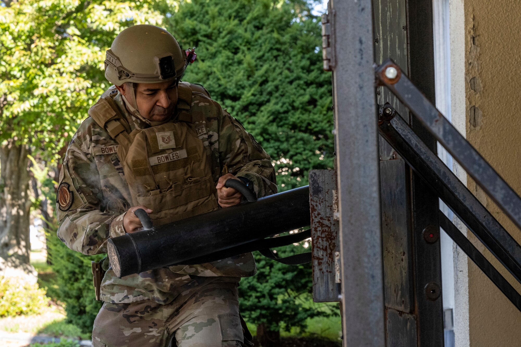 Airman batter down door with battering ram.