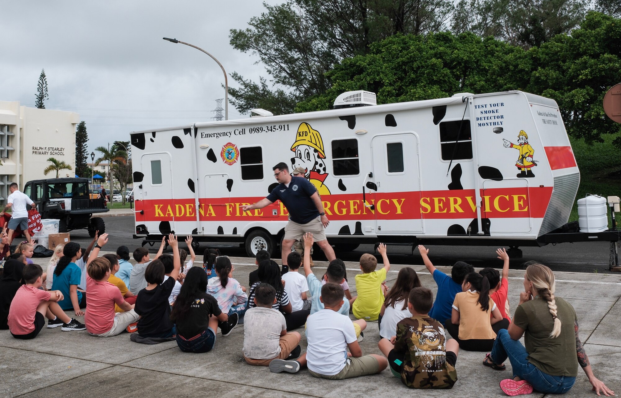 Children listen to fire prevention presentation outside of their school