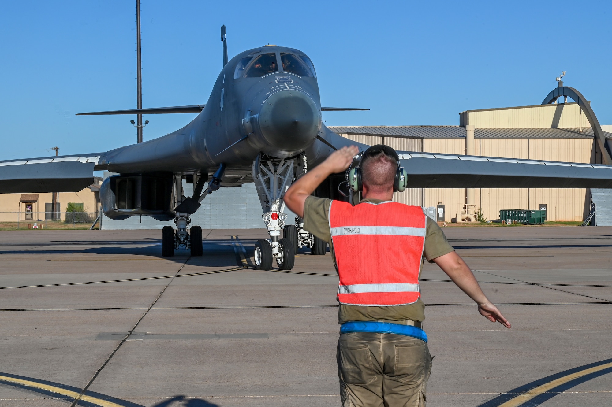 Airman 1st Class Brady Hackler, 7th Aircraft Maintenance Squadron crew chief, marshals a B-1B Lancer for takeoff at Dyess Air Force Base, Texas, Oct. 11, 2023, to kick off a U.S. European Command Bomber Task Force deployment. Strategic bomber missions enhance the readiness and training necessary to respond to any potential crisis or challenge across the globe. (U.S. Air Force photo by Senior Airman Sophia Robello)