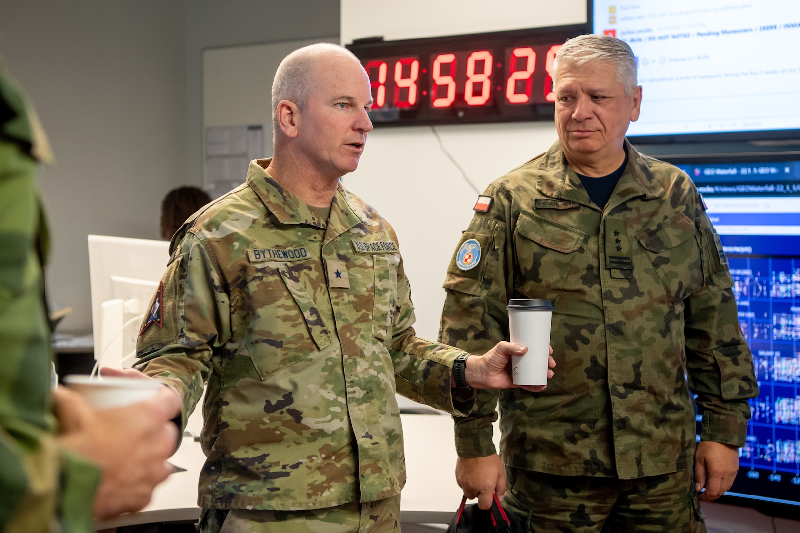 Two men in military uniforms speak to each other