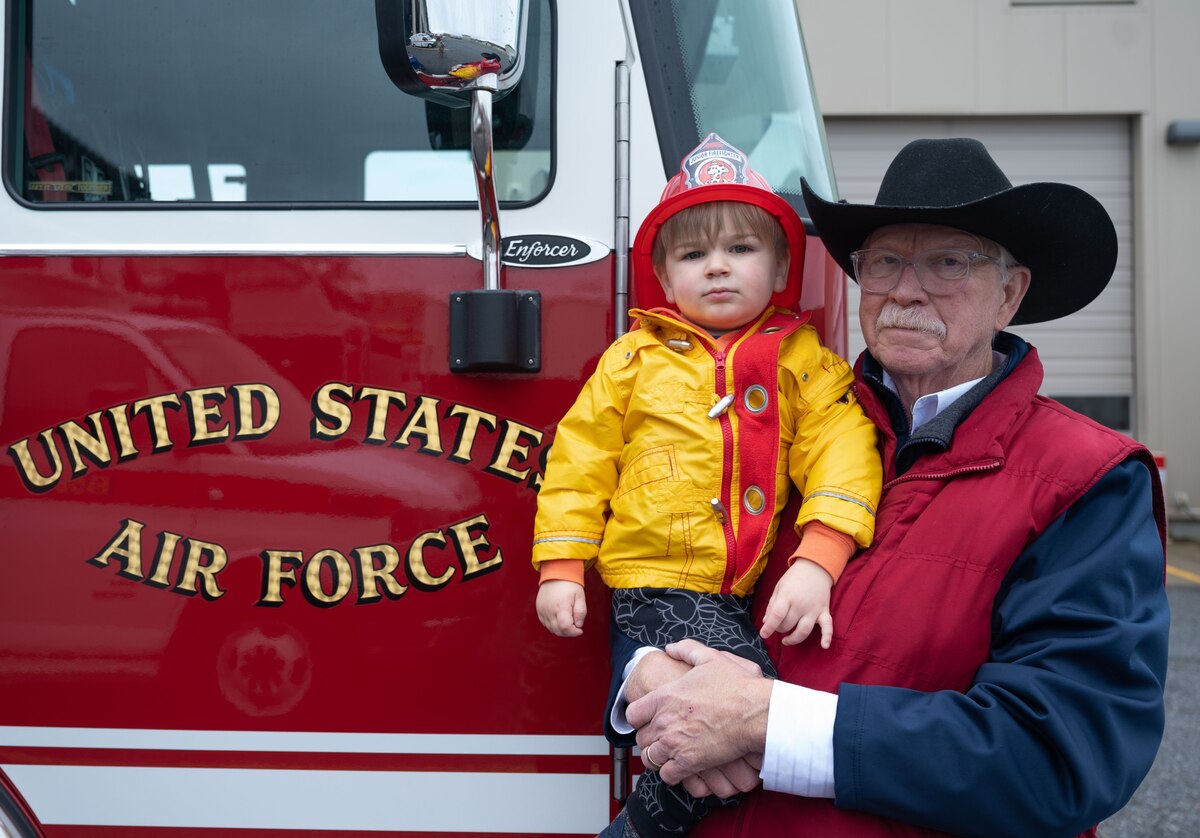 Joe Yacyshyn poses with his grandson, Teddy Swyka, at the 10th Annual Military Appreciation Day and 2023 Fire Prevention Week Open House at Dover Air Force Base, Delaware, Oct. 14, 2023. The events included food, games, face painting and bouncy houses. (U.S. Air Force photo by Senior Airman Cydney Lee)