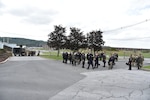 Photo shows two groups of people in police uniforms standing on opposite sides of a field.