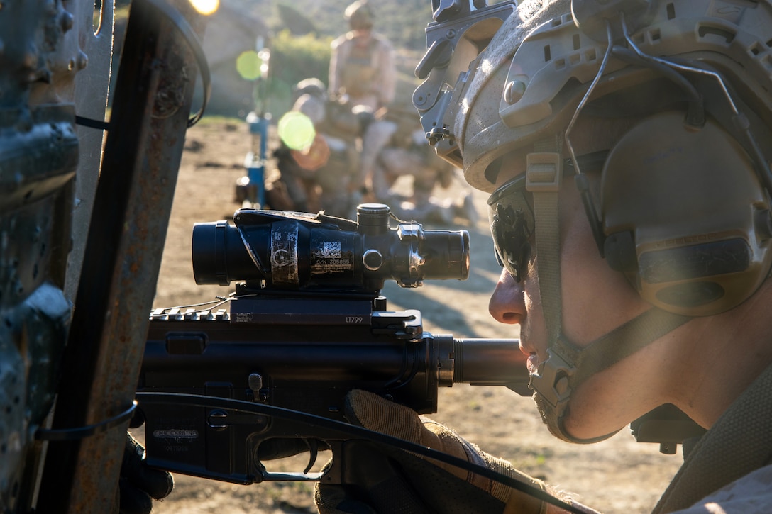 A soldier holds a weapon while looking through the scope during a training exercise.