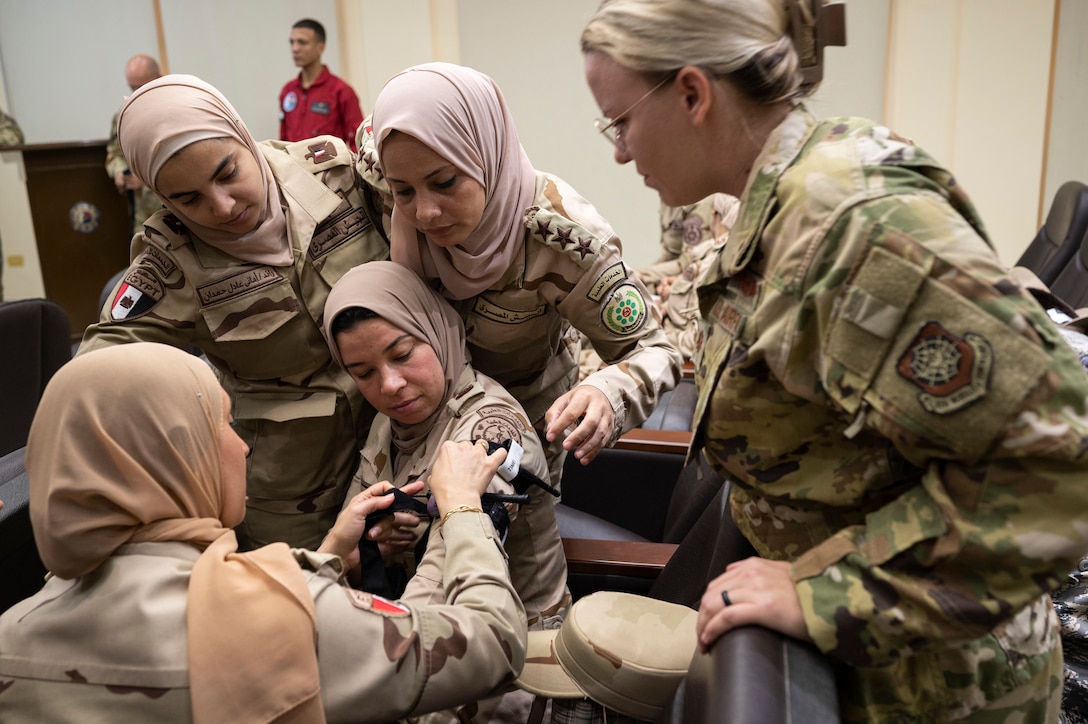 Service members watch as one applies a tourniquet.