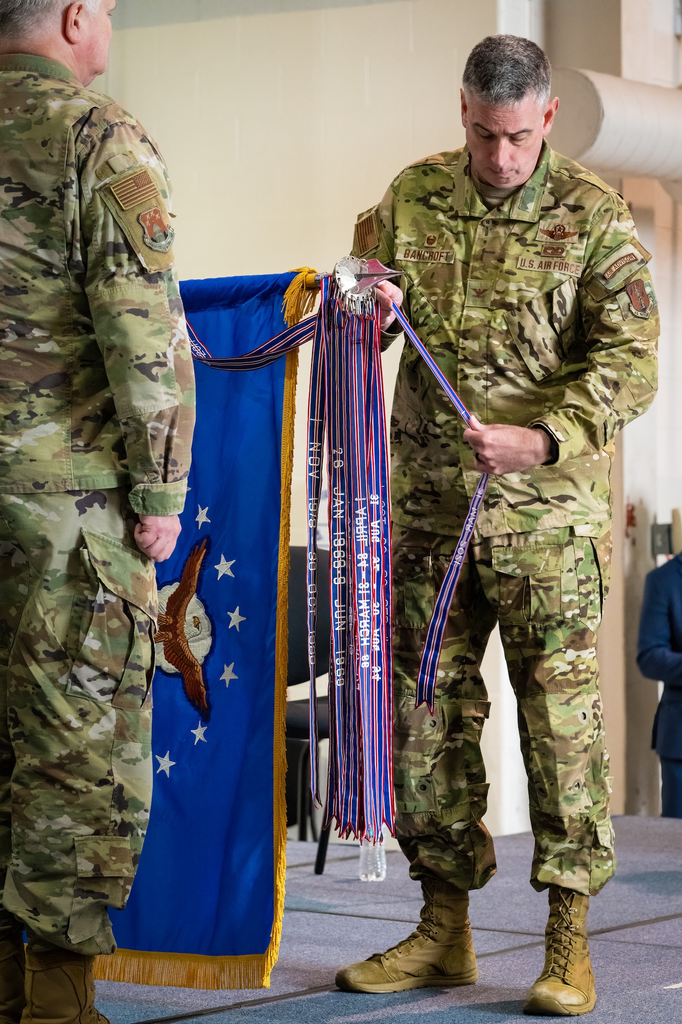 Col. Bruce Bancroft, commander of the 123rd Airlift Wing, attaches a streamer to the unit colors representing its 20th Air Force Outstanding Unit Award during a ceremony at the Kentucky Air National Guard Base in Louisville, Ky., Oct. 14, 2023. The honor recognizes superior achievement in a broad spectrum of missions around the world since 2019. (U.S. Air National Guard photo by Dale Greer)