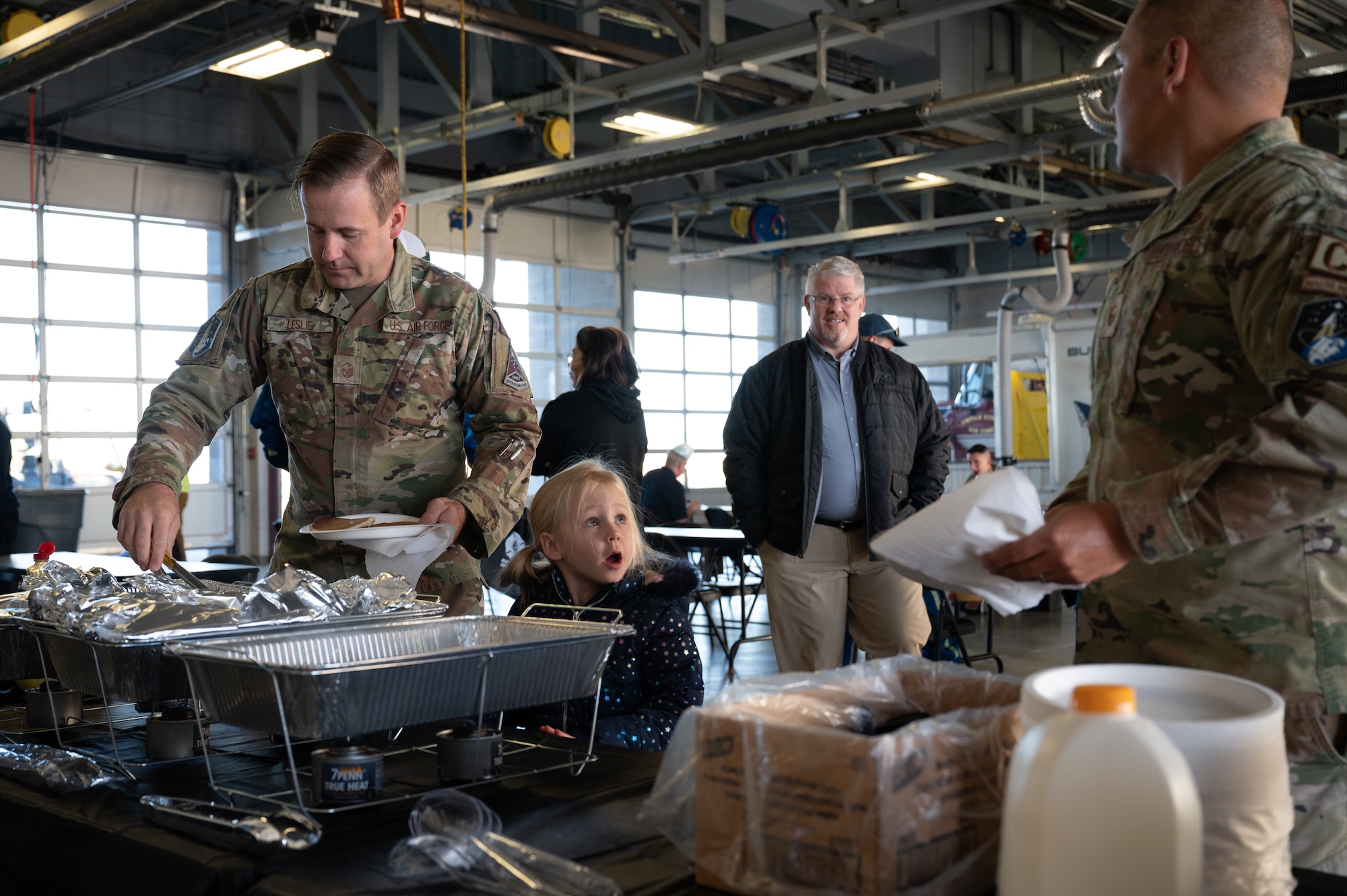 A servicemember and his daughter in line for food.