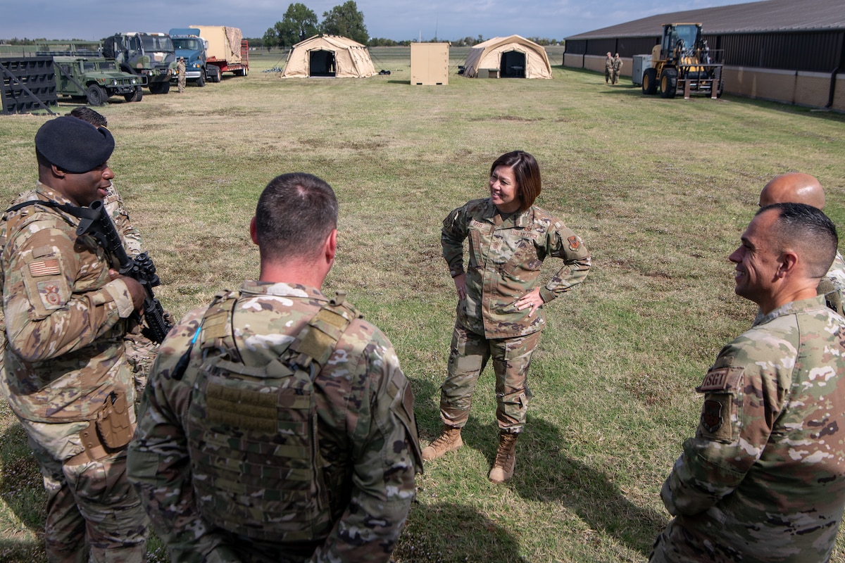 a woman speaks to a group of Airmen