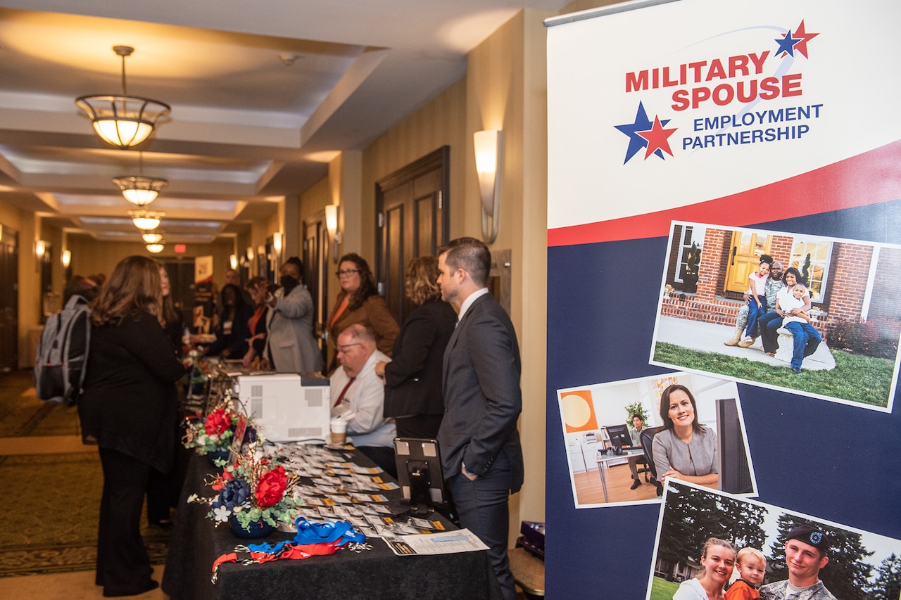 People mill around a table near a banner that says, “Military Spouse Employment Partnership.”