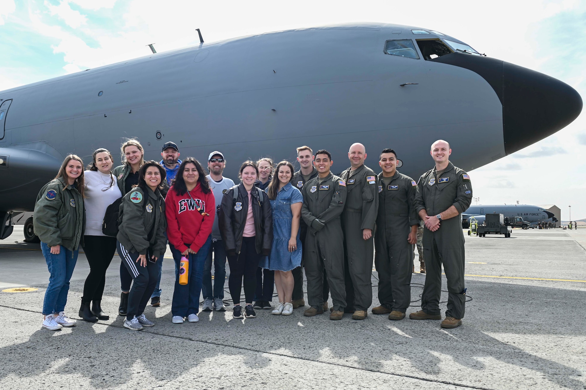 Group of spouses and aircrew take a group photo in front of a KC-135