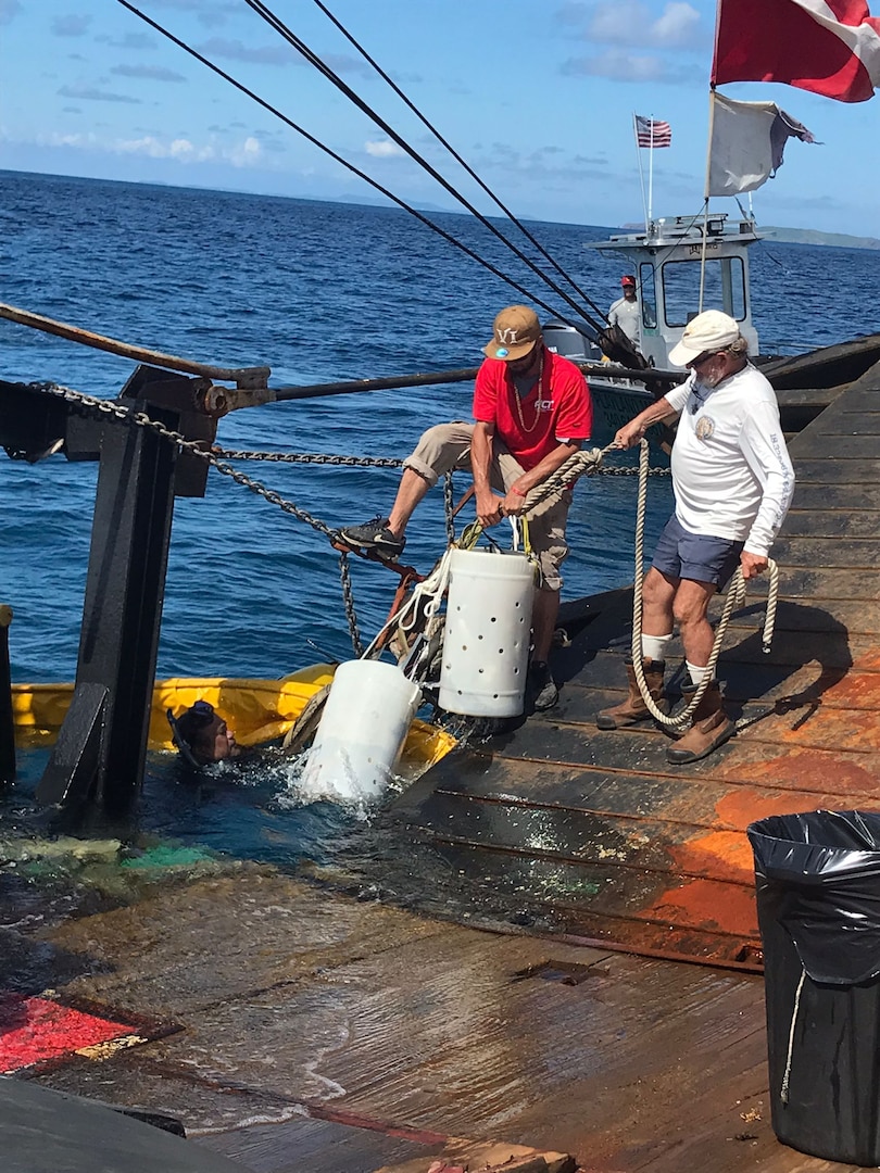 Salvors take collected debris from divers and bring it aboard the Bonnie G for disposal off Cyril E. King Airport, St. Thomas, Oct. 15, 2023. Divers removed approximately 2,500 lbs of debris from the ocean floor. (U.S. Coast Guard photo)