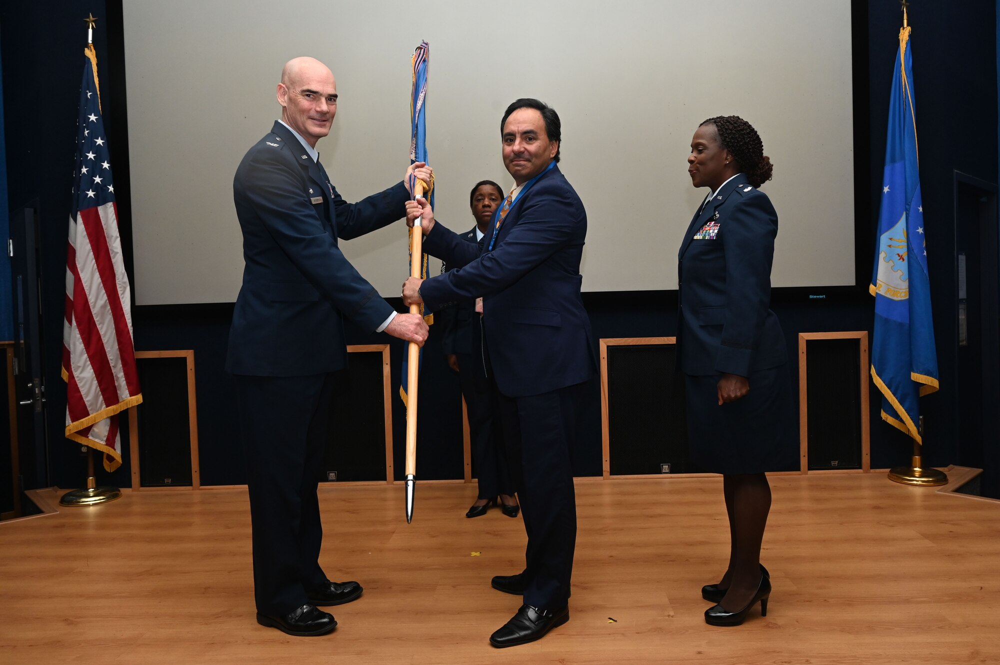 Col. William Gutermuth, 433rd Airlift Wing commander, hands the 433rd AW guidon to Augie Cortez, Jr., owner of Augie’s BBQ, during the Honorary Commanders’ Induction Ceremony on Joint Base San Antonio-Lackland, Texas, Oct. 15, 2023. Honorary commanders have opportunities to learn about their units and commanders through C-5M Super Galaxy tours, demonstrations, events and flights.