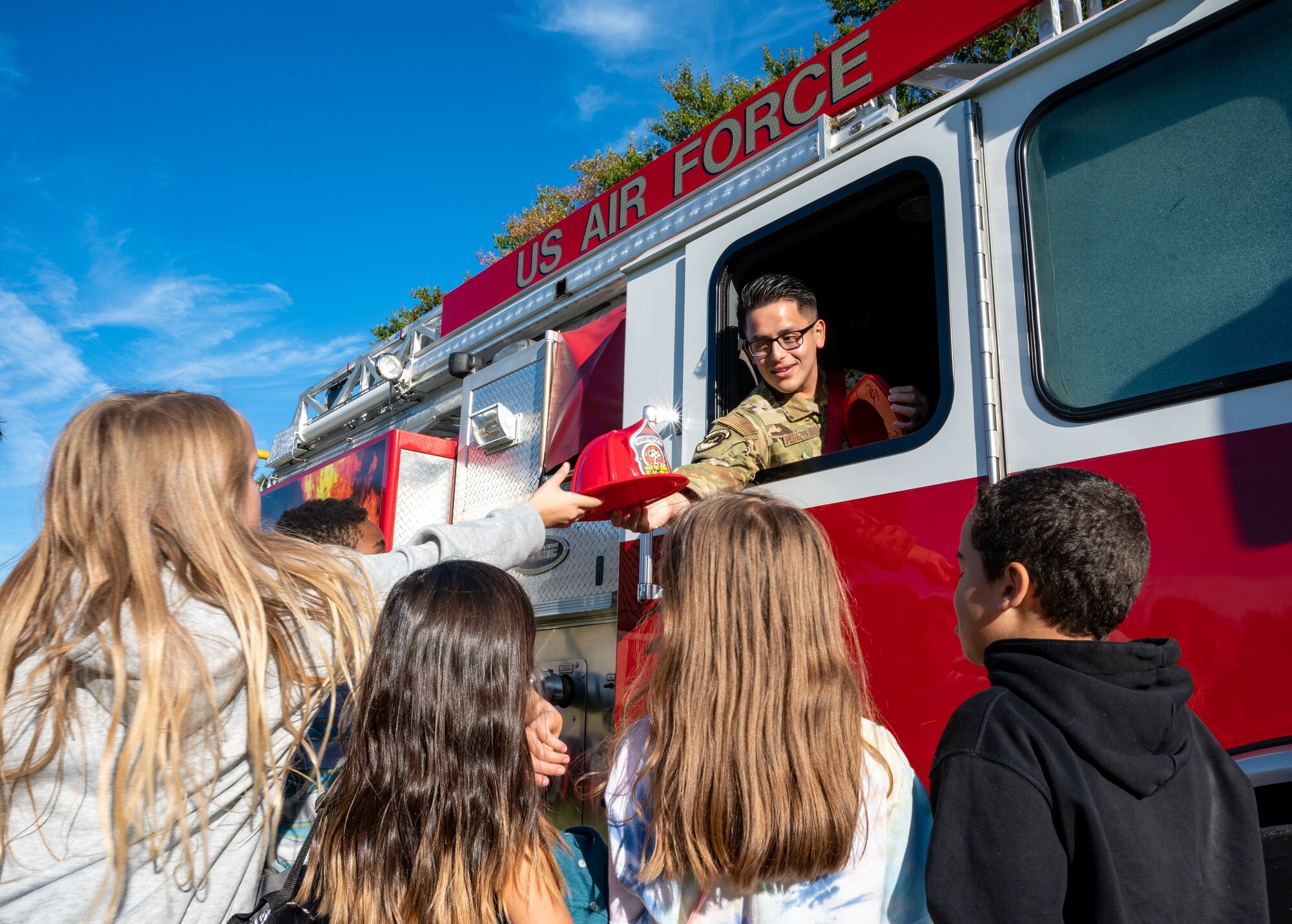U.S. Air Force Staff Sgt. Leovardo Perez-Tejeda, 436th Civil Engineer Squadron firefighter, hands out fireman hats to kids before the 2023 Fire Prevention Week Parade at Dover Air Force Base, Delaware, Oct. 13, 2023. Fire Prevention Week is a nation-wide observation that teaches people how to stay safe in case of a fire. (U.S. Air Force photo by Airman 1st Class Amanda Jett)