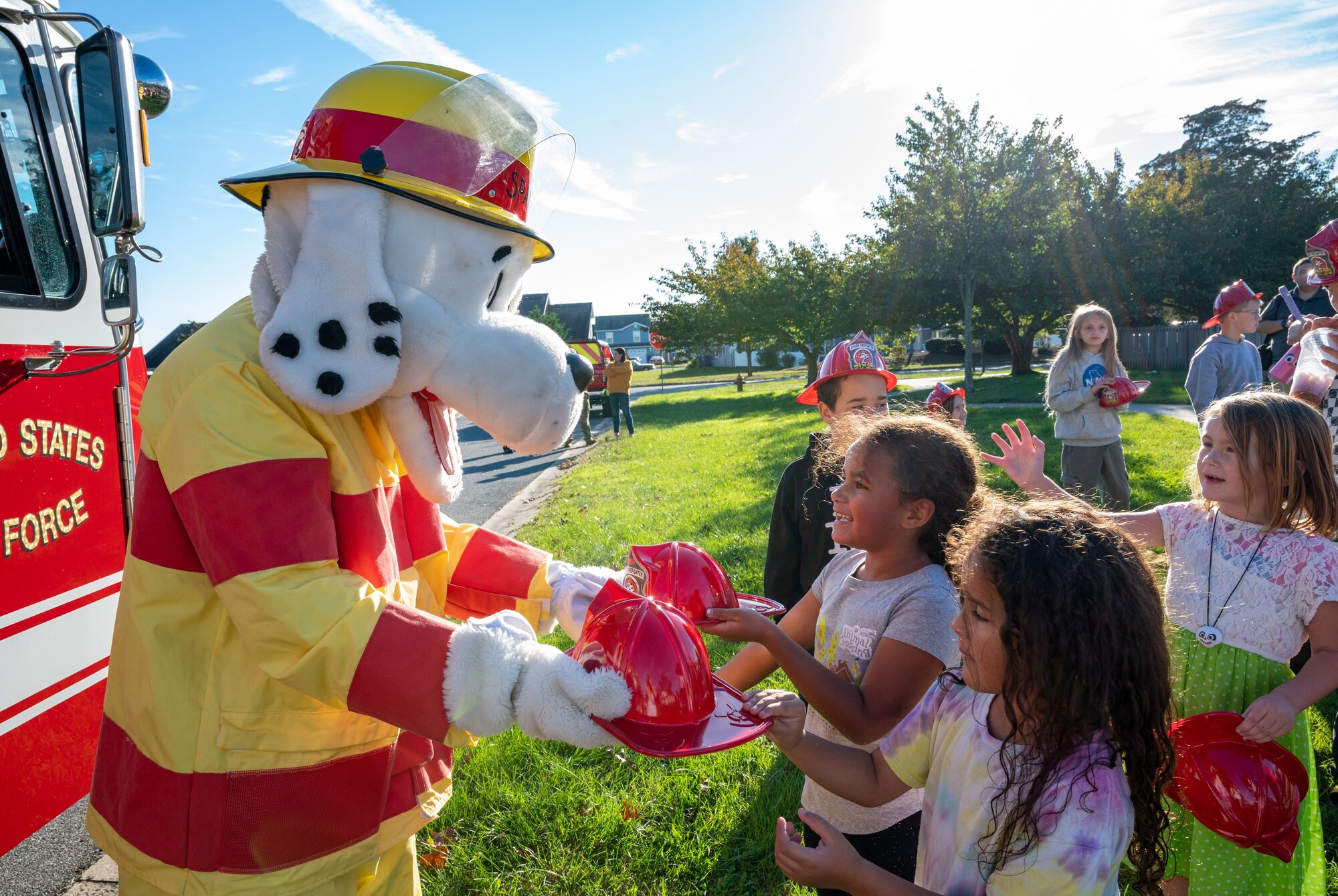 Sparky, the Fire Prevention Week mascot, hands out fireman hats before the 2023 Fire Prevention Week Parade on Dover Air Force Base, Delaware, Oct. 13, 2023. Fire Prevention Week is a nation-wide observation that teaches people how to stay safe in case of a fire. (U.S. Air Force photo by Airman 1st Class Amanda Jett)