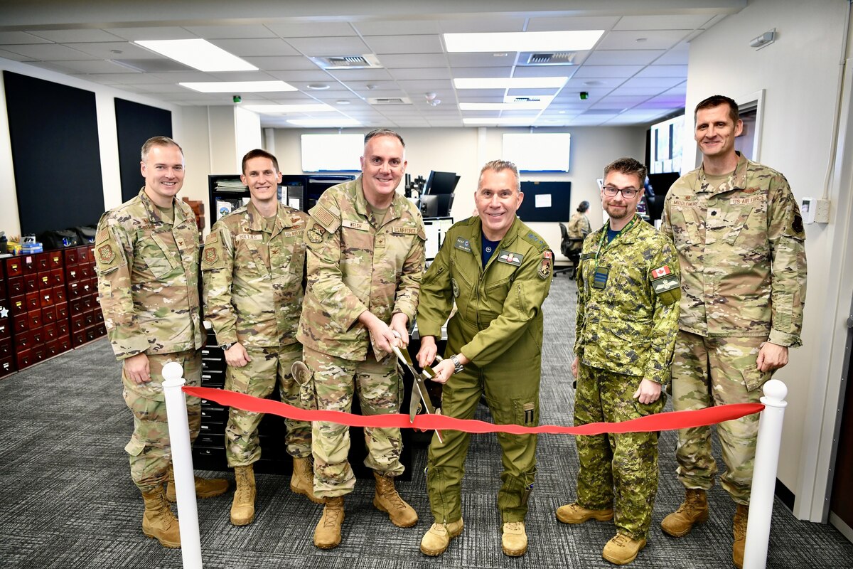 Men cutting a red ribbon