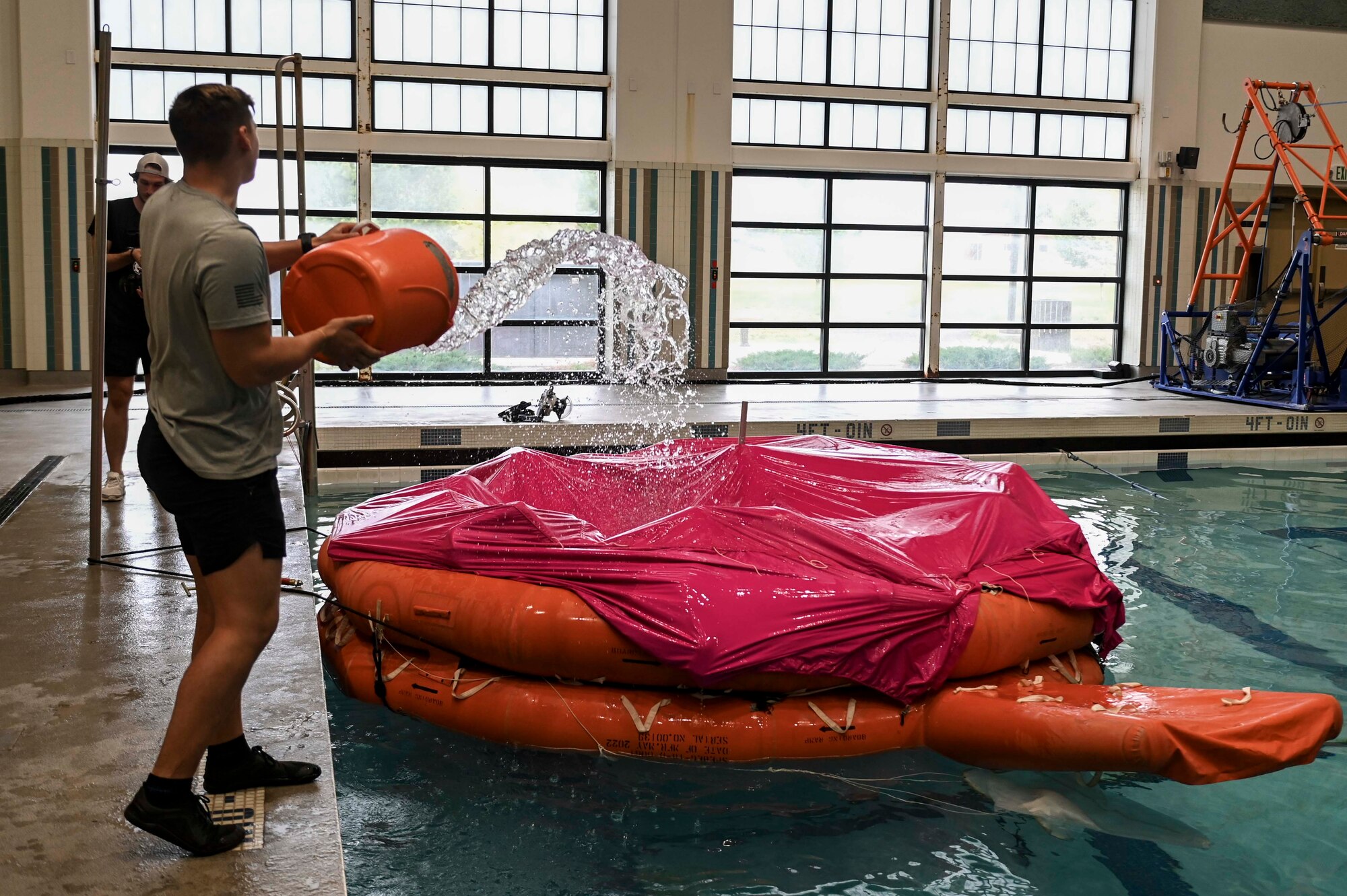 A SERE instructor dumps bucket of water onto raft