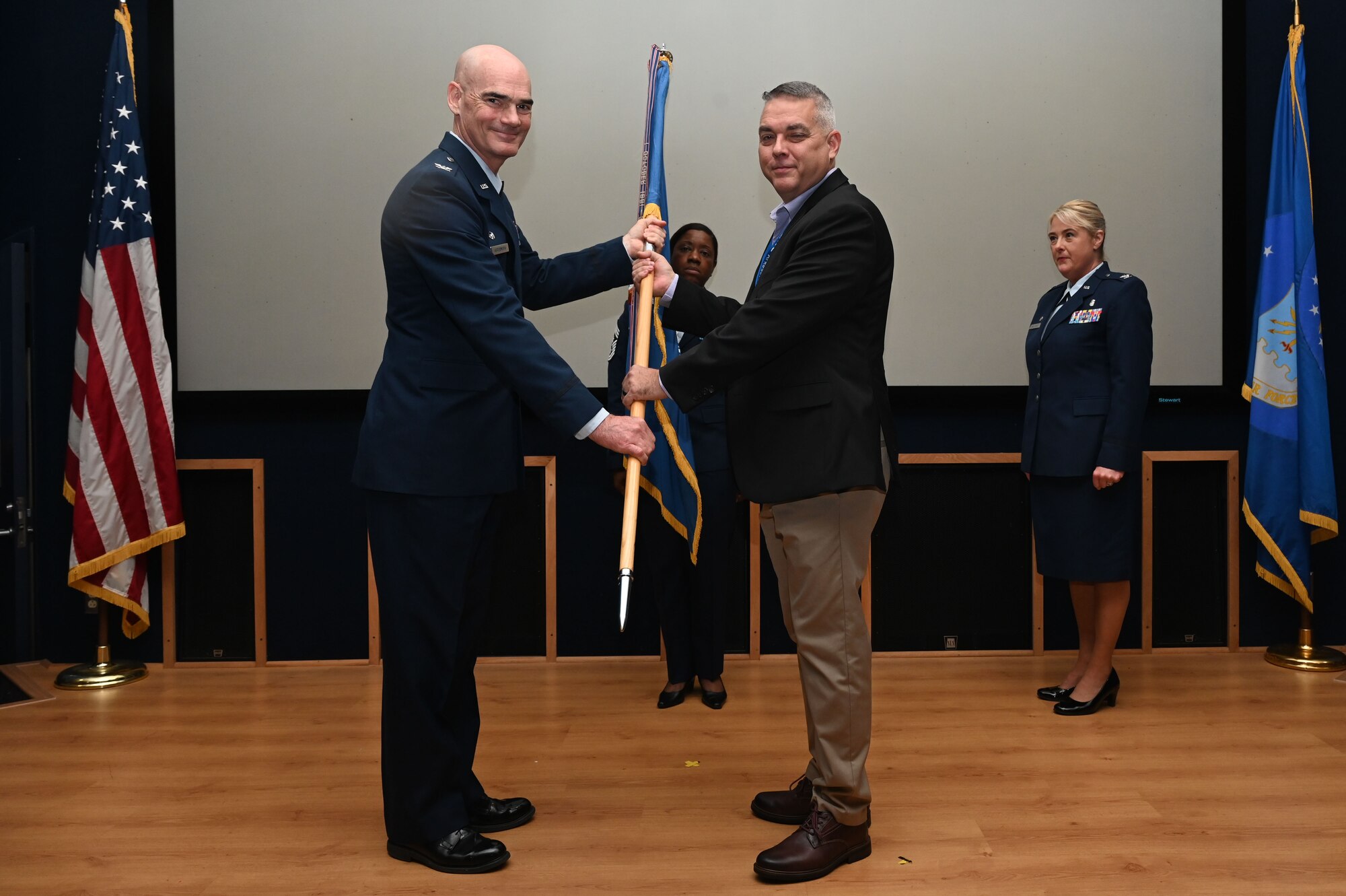 Col. William Gutermuth, 433rd Airlift Wing commander, hands the 433rd AW guidon to Alex Melo, community relations manager at Brooks Real Estate, during the Honorary Commanders’ Induction Ceremony on Joint Base San Antonio-Lackland, Texas, Oct. 15, 2023. Honorary commanders have opportunities to learn about their units and commanders through C-5M Super Galaxy tours, demonstrations, events and flights.