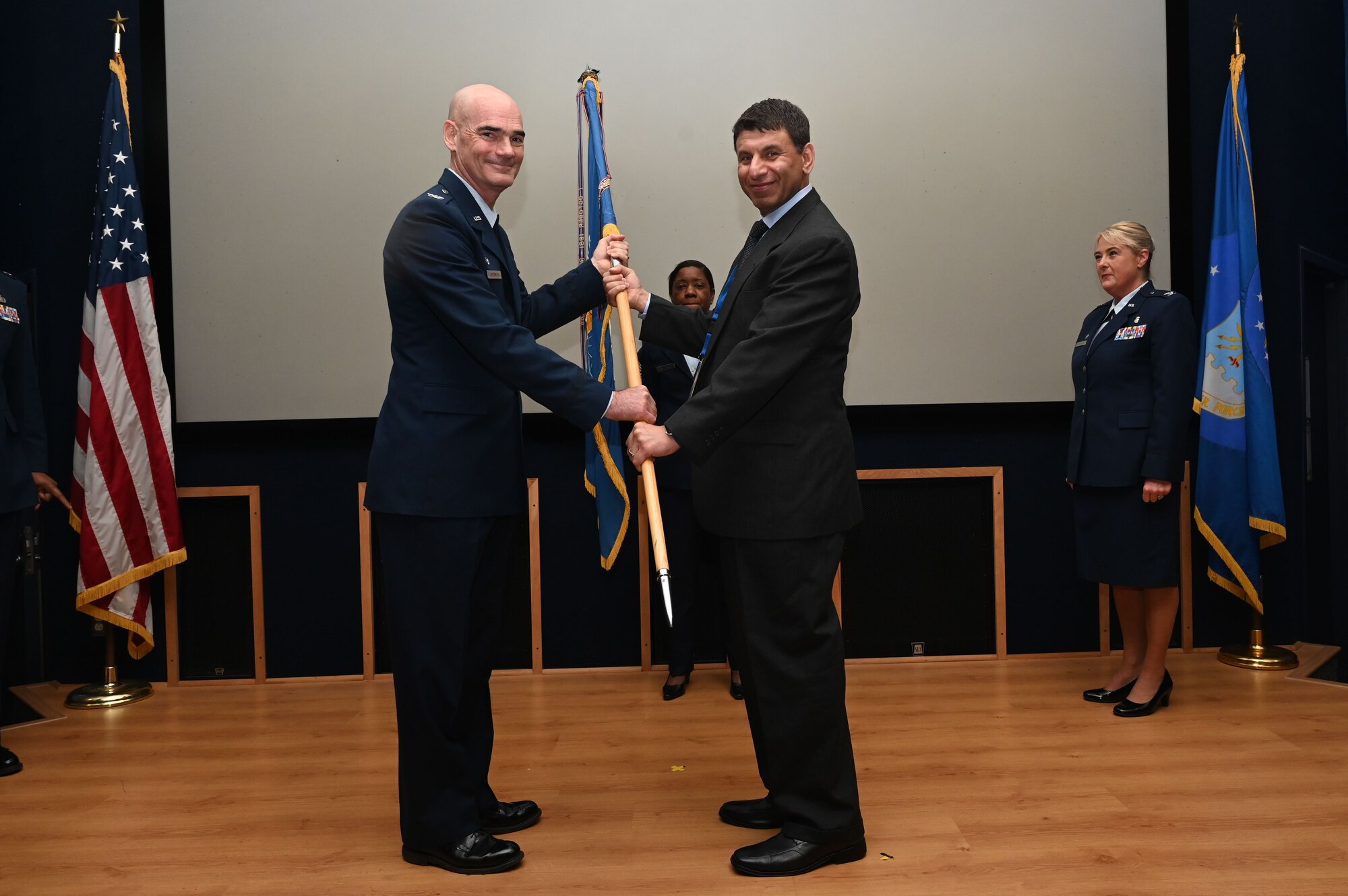 Col. William Gutermuth, 433rd Airlift Wing commander, hands the 433rd AW guidon to Dr. Suhail Daraiseh, chiropractor at Sana Welllness & Health, during the Honorary Commanders’ Induction Ceremony in on Joint Base San Antonio-Lackland, Texas, Oct. 15, 2023. Honorary commanders have opportunities to learn about their units and commanders through C-5M Super Galaxy tours, demonstrations, events and flights.