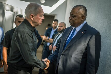 Two men in civilian attire shake hands.