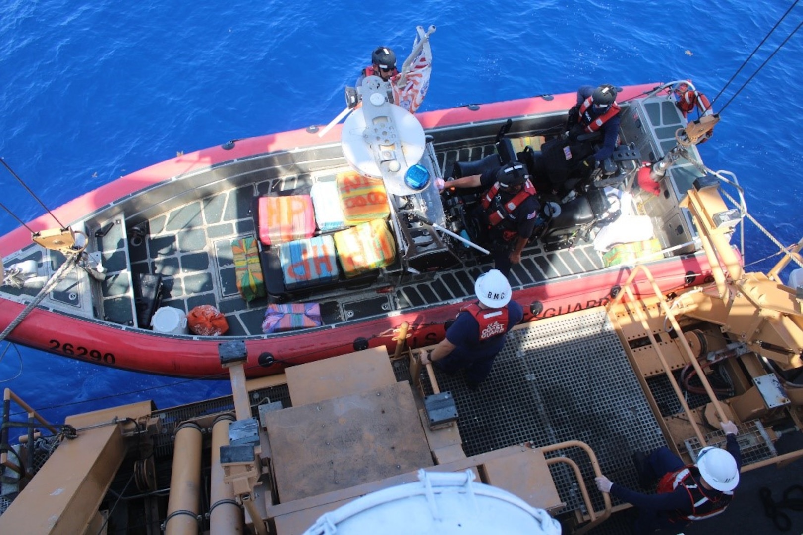 Bags of interdicted cocaine are documented and transferred from a Coast Guard cutter’s small boat