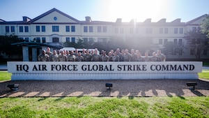 A group of people stand in front of a building's sign that says "HQ Air Force Global Strike Command"
