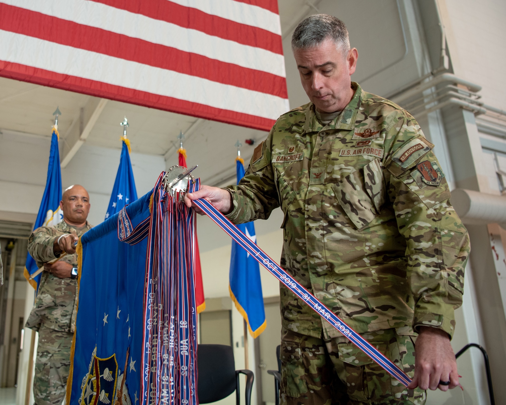 Col. Bruce Bancroft, 123rd Airlift Wing commander, pins a streamer to the unit colors during a ceremony at the Kentucky Air National Guard Base in Louisville, Ky., Oct. 14, 2023. The streamer signifies the unit’s selection for its 20th Air Force Outstanding Unit Award, continuing its legacy as one of the most decorated organizations in U.S. Air Force history. (U.S. Air National Guard photo by Tech. Sgt. Joshua Horton)