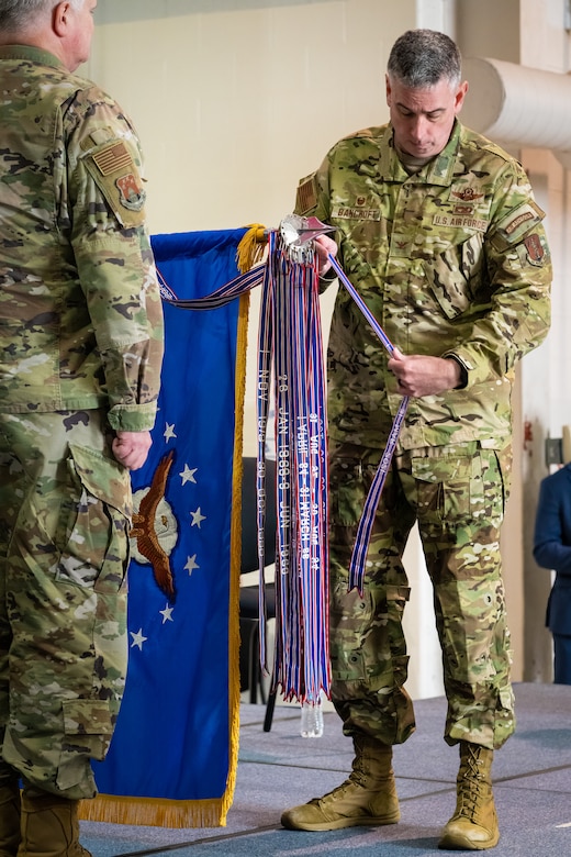 Col. Bruce Bancroft, commander of the 123rd Airlift Wing, attaches a streamer to the unit colors representing its 20th Air Force Outstanding Unit Award during a ceremony at the Kentucky Air National Guard Base in Louisville, Ky., Oct. 14, 2023. The honor recognizes superior achievement in a broad spectrum of missions around the world since 2019. (U.S. Air National Guard photo by Dale Greer)