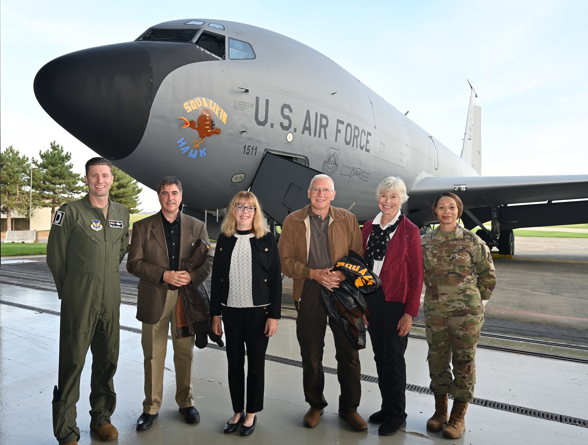 U.S. Air Force Col. Ryan Garlow, left, 100th Air Refueling Wing commander, and Chief Master Sgt. Tiffany Griego, right, 100th ARW command chief, show of the latest heritage nose art, “Squawkin Hawk,” on a KC-135 Stratotanker with family members of the original World War II crew of “Squawkin Hawk,” a B-17 Flying Fortress, at Royal Air Force Mildenhall, England, Oct. 10, 2023. The 100th Air Refueling Wing held a ceremony to unveil two additional heritage nose arts to its fleet, in honor of those who served at Thorpe Abbotts during World War II, many of whom made the ultimate sacrifice. (U.S. Air Force photo by Karen Abeyasekere)