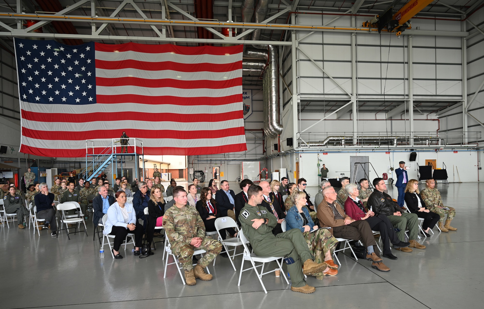 Audience members listen to a speech by Chris Barrett, husband of Laura Barrett, grand-niece of Lt. Harry Edeburn, co-pilot on the 100th Bomb Group’s original “Squawkin Hawk” B-17 Flying Fortress during World War II, at a nose art dedication ceremony at Royal Air Force Mildenhall, England, Oct. 10, 2023. The 100th Air Refueling Wing unveiled two new heritage nose art on their KC-135 Stratotanker fleet, one of which was “Squawkin Hawk.” (U.S. Air Force photo by Karen Abeyasekere)
