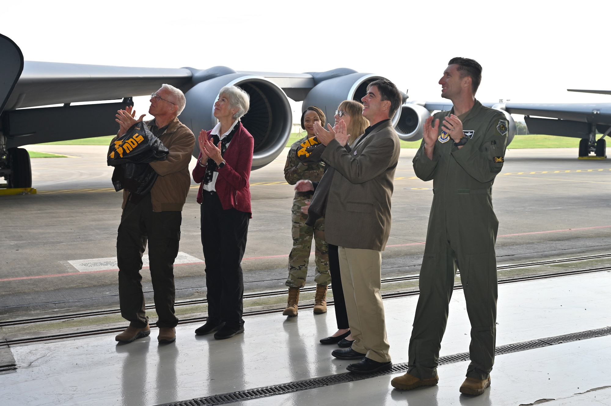 Family members of original crew members of the B-17 Flying Fortress known as “Squawkin Hawk,” assigned to the 100th Bomb Group, Thorpe Abbotts, Norfolk, during World War II, along with U.S. Air Force Chief Master Sgt. Tiffany Griego, center, 100th Air Refueling Wing command chief, and Col. Ryan Garlow, right, 100th ARW commander, look on in delight as the newest “Squawkin Hawk” nose art is unveiled Oct. 10, 2023. RAF Mildenhall’s heritage nose art honors those who served at Thorpe Abbotts during World War II, many of whom made the ultimate sacrifice. (U.S. Air Force photo by Karen Abeyasekere)