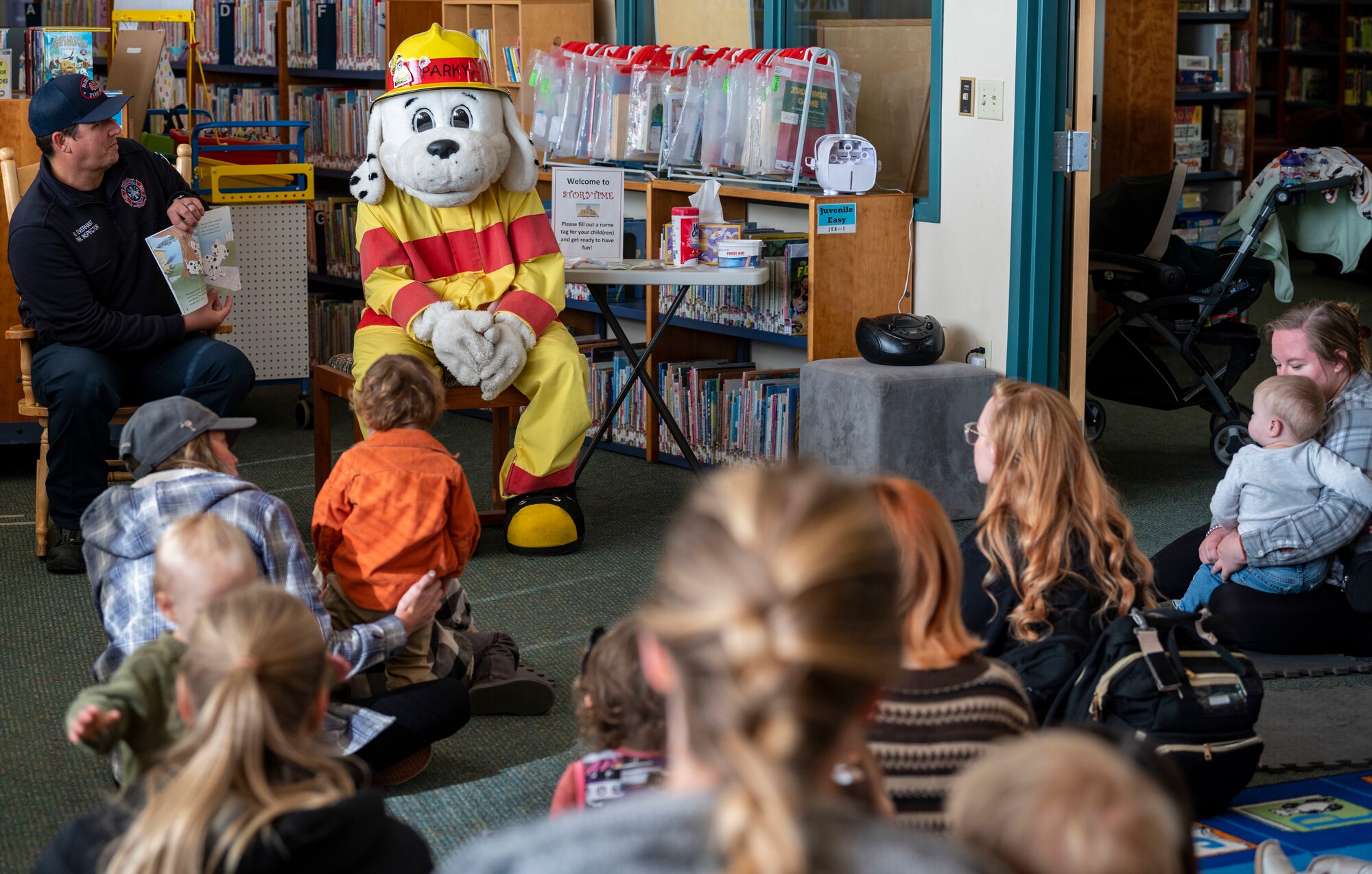 A fire inspector reads to children at the library with Sparky the Fire Dog.