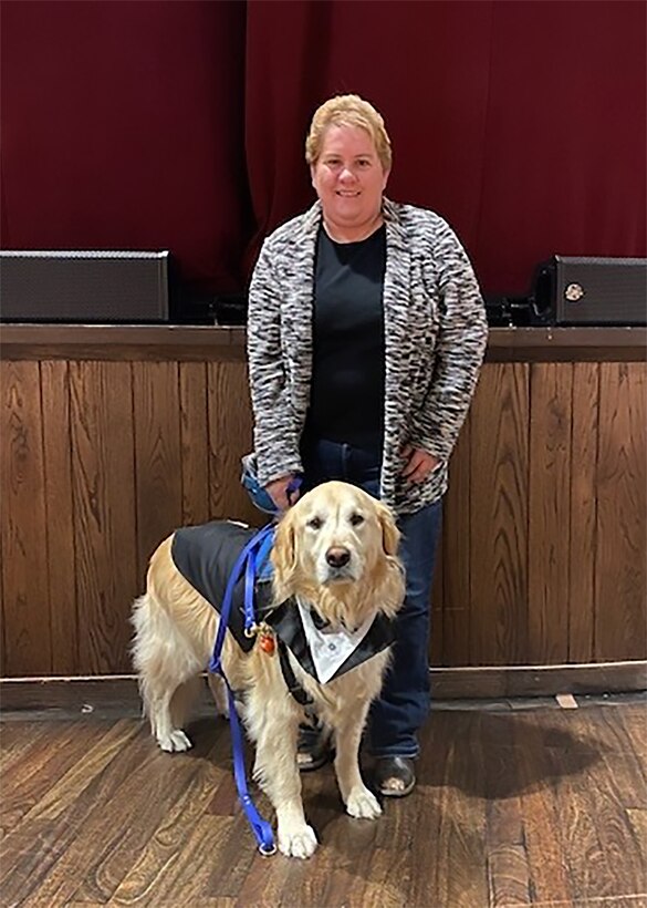 A smiling woman with her service dog.