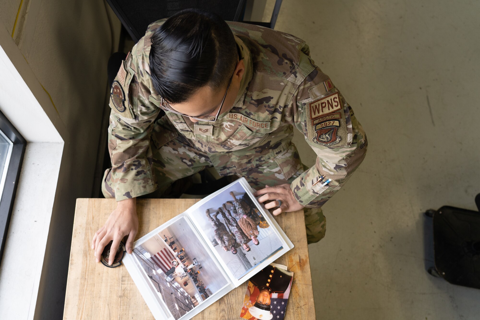 U.S. Air Force Tech. Sgt. Jorge L. Galvez, armament support section chief assigned to the 3rd Munitions squadron at Joint Base Elmendorf-Richardson, Alaska, poses with family and personal photos displaying his previous career field as an Aviation ordnance technician in the United States Marine Corps Oct. 13, 2023.